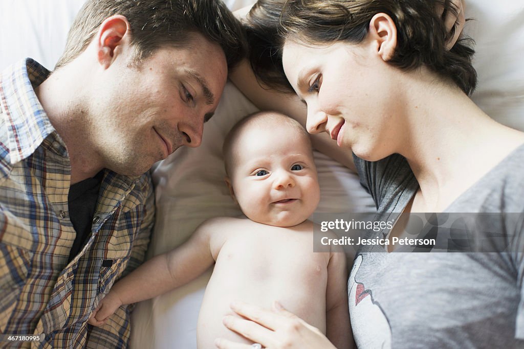 USA, California, Orange County, Parents and baby son (2-5 months) lying on bed
