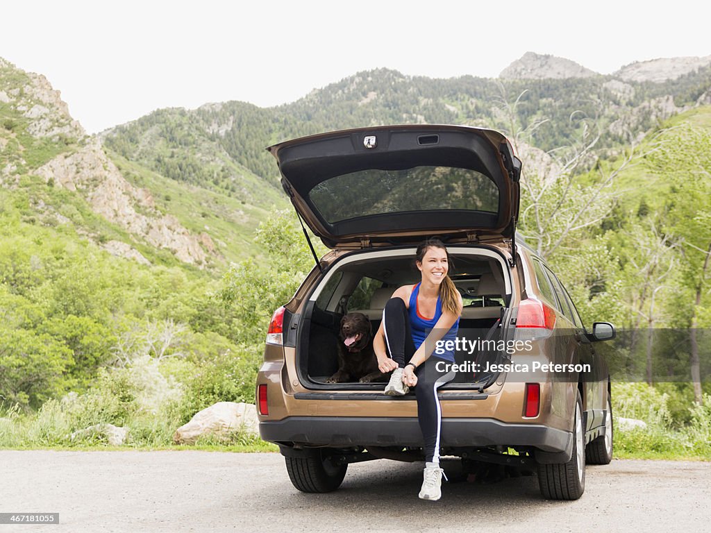 USA, Utah, Salt Lake City, Woman wearing sportswear sitting at car trunk with dog