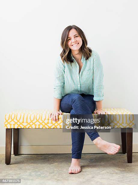 portrait of young woman smiling - legs crossed at knee stock pictures, royalty-free photos & images