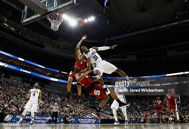 Dylan Ennis of the Villanova Wildcats puts up a shot while being guarded by Caleb Martin and Ralston Turner of the North Carolina State Wolfpack in...