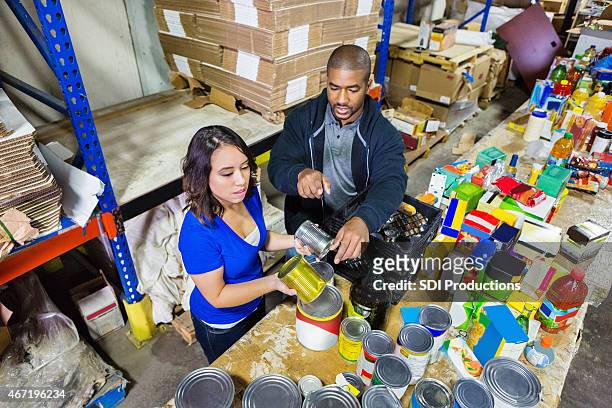 volunteers sorting donations in large food bank distribution warehouse - best before stock pictures, royalty-free photos & images