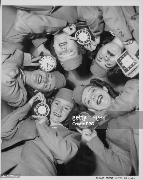Air line stewardesses posing with clocks, practicing for the imminent time change; Ann Stubbs, Maxine Evans, Jean Goodnight, Phyllis Clay and Peggy...