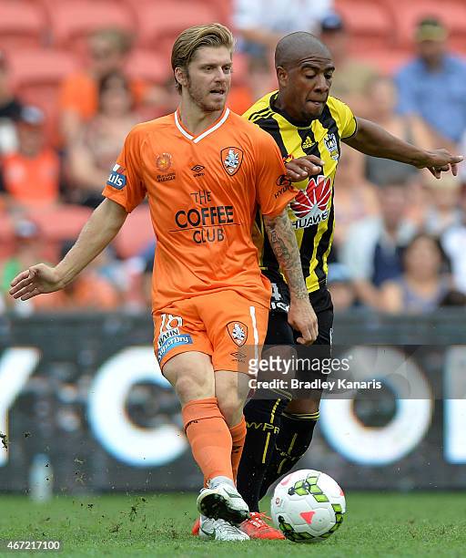 Luke Brattan of the Roar is challenged by the defence of Roy Krishna of the Phoenix during the round 22 A-League match between the Brisbane Roar and...