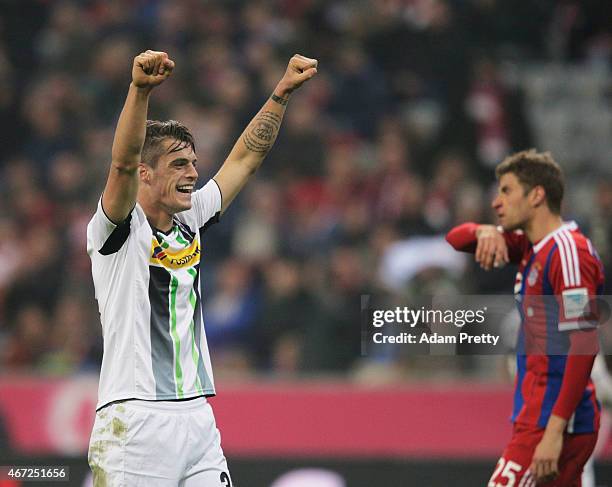 Granit Xhaka of Borussia Moenchengladbach celebrates victory in front of a dejected Thomas Mueller of FC Bayern Muenchen during the Bundesliga match...