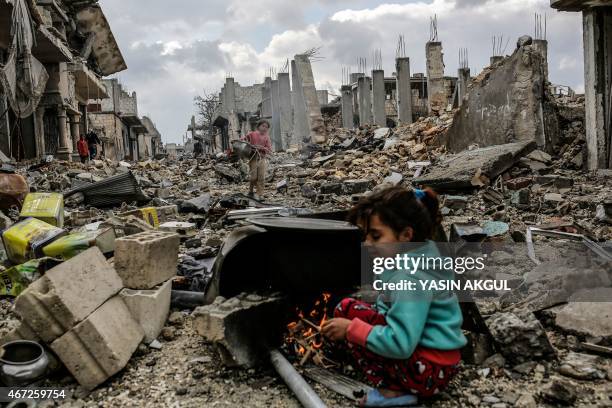 Kurdish Syrian girls are pictured among destroyed buildings in the Syrian Kurdish town of Kobane, also known as Ain al-Arab, on March 22, 2015. AFP...