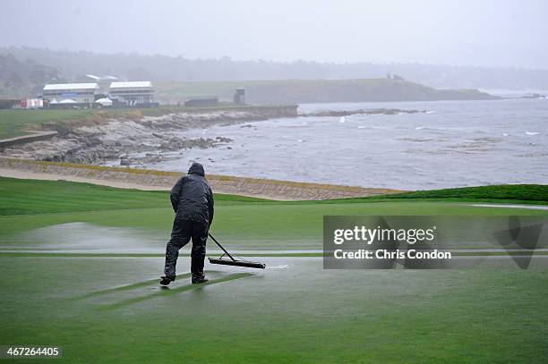 Members of the grounds crew work on the 18th green during a weather delay during the first round of the AT&T Pebble Beach National Pro-Am at Pebble...