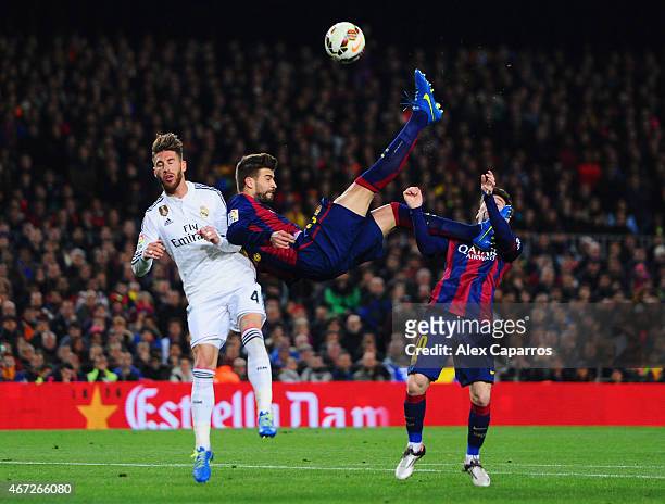 Lionel Messi of Barcelona looks on as Gerard Pique of Barcelona attempts an overhead kick under challenge from Sergio Ramos of Real Madrid CF during...