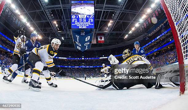 Goalie Niklas Svedberg the Boston Bruins makes a glove save during the second period while teammate Adam McQuaid as well as Steven Stamkos and...
