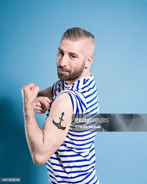bearded sailor man showing his anchor tatoo - sailor arm stockfoto's en -beelden