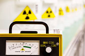 Geiger counter with yellow hazard signs in row fading behind