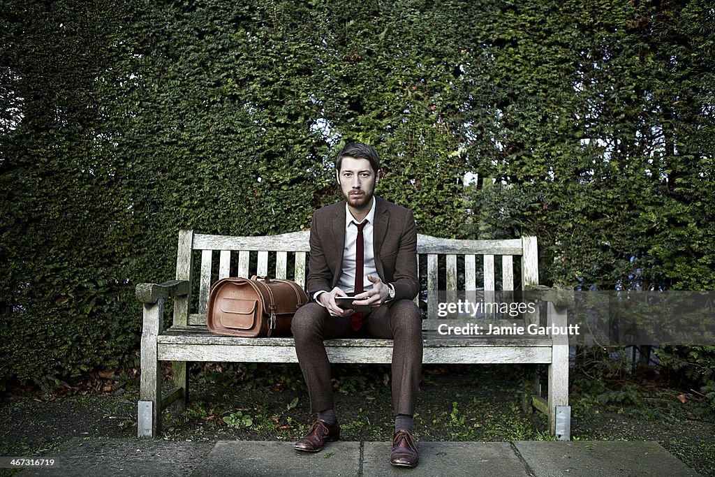 Portrait of gentleman sitting on bench with tablet computer