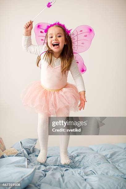 girl wearing fairy costume jumping on bed. - fairy costume stock pictures, royalty-free photos & images
