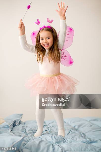 girl wearing fairy costume jumping on bed. - costume wing stock pictures, royalty-free photos & images