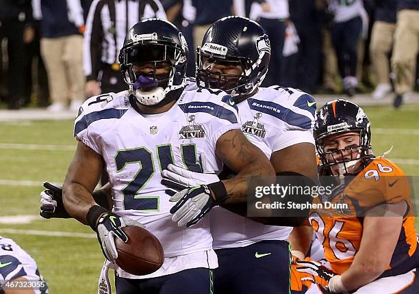 Running back Marshawn Lynch of the Seattle Seahawks celebrates his 1-yard touchdown with teammate tackle Alvin Bailey in the second quarter against...