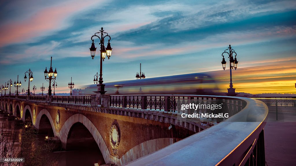 Bordeaux tram passing over the stone bridge at daw