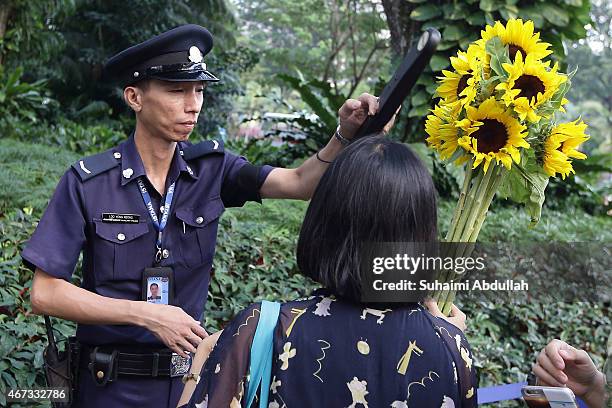 Policeman inspects the flowers for security as people queue to pay tribute at Istana following the passing of former Prime Minister Lee Kuan Yew on...