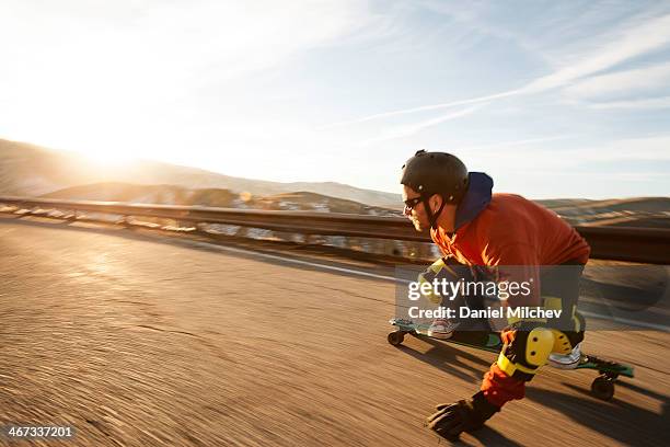 lonboard skateboarder going down a road at sunset. - longboard skating stock pictures, royalty-free photos & images