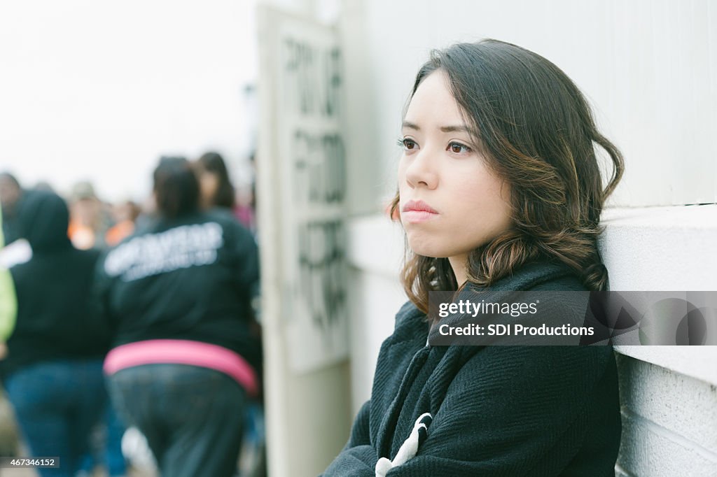 Depressed young woman standing in line at city food bank
