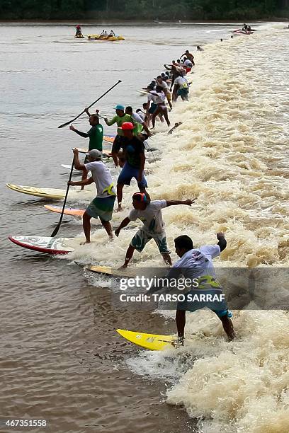 People surf on the wave of a tidal bore known as "Pororoca" during the annual surfing Pororoca festival in Sao Domingos do Capim, around 140km from...
