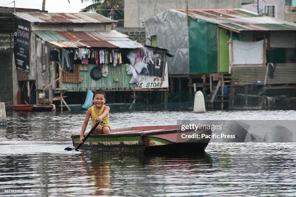 A young boy smiles as he paddles his way through the flooded...