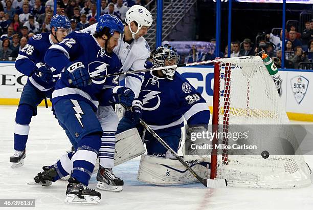 Frazer McLaren of the Toronto Maple Leafs is sandwiched between goalie Ben Bishop and defender Jean-Philippe Cote of the Tampa Bay Lightning at the...