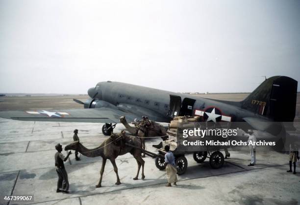 Local workers unload a Douglas Dakota Transport airplane at the U.S. Army Air Force Base in Karachi,India.