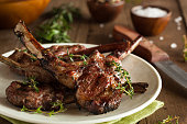 Grilled lamb chops organized on a white plate on wood