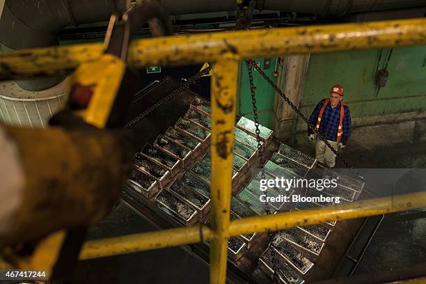 Worker watches as a mechanical hoist is used to lift newly cast silver bullion bars from the factory floor at the KHGM Polska Miedz SA smelting plant...