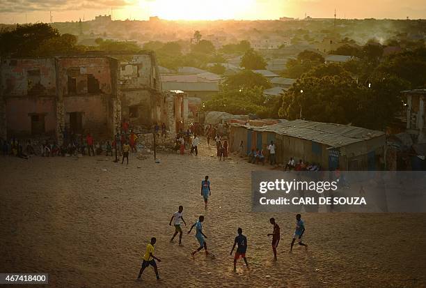 Somalis play football as the sun sets in Mogadishu on March 24, 2015. AFP PHOTO/Carl de Souza