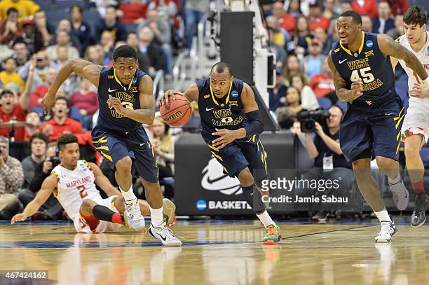 Jevon Carter of the West Virginia Mountaineers controls the ball against the Maryland Terrapins as Juwan Staten of the West Virginia Mountaineers and...