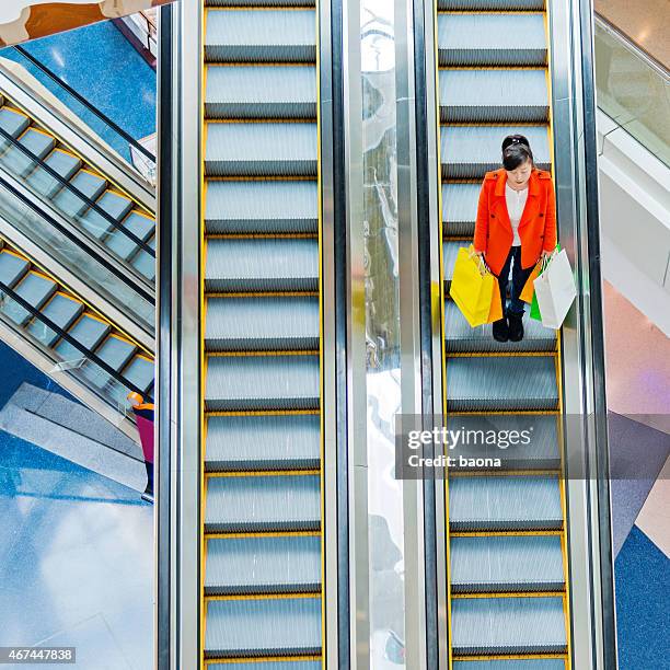 female shopper standing on escalator - shopping bag top view stock pictures, royalty-free photos & images
