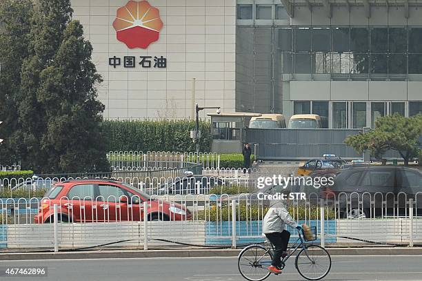 Citizen cycles past the headquarters of the China National Petroleum Corporation in Beijing on March 25, 2015. The inexorable decline of the euro...