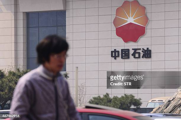 People walk by the headquarters of the China National Petroleum Corporation in Beijing on March 25, 2015. The inexorable decline of the euro offers...