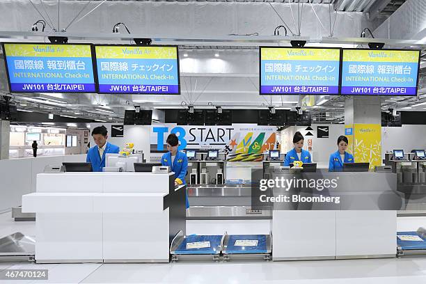Ground staff stand behind a check-in counter for Vanilla Air at Terminal 3 of Narita Airport in Narita, Japan, on Wednesday, March 25, 2015. The...