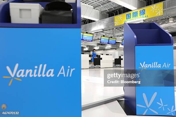 Member of ground staff stands behind a check-in counter for Vanilla Air at Terminal 3 of Narita Airport in Narita, Japan, on Wednesday, March 25,...