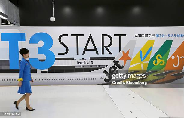 Vanilla Air ground staff member walks past a sign announcing the start of Terminal 3 at Narita Airport in Narita, Japan, on Wednesday, March 25,...