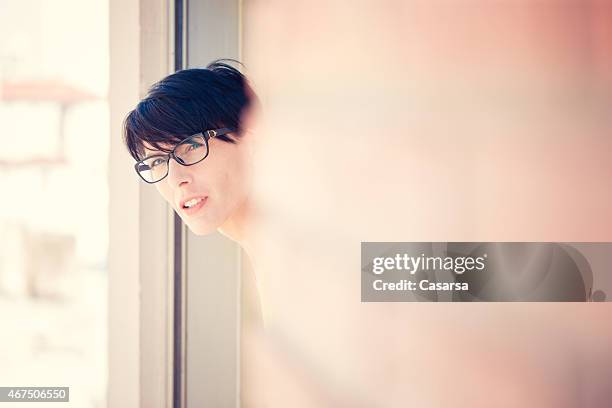 mujer mirando por la ventana - mirar alrededor fotografías e imágenes de stock