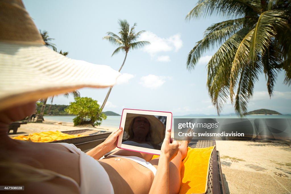 Jeune femme sur la plage à l'aide de Tablette numérique