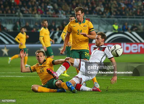 Benedikt Hoewedes of Germany is challenged by Alex Wilkinson and Luke DeVere of Australia during the international friendly match between Germany and...