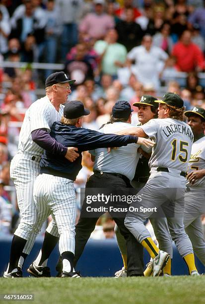 Manager Buck Showalter of the New York Yankees gets held back by coach Frank Howard and Oakland Athletics coach Rene Lachemann while attempting to...