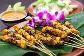 Chicken satay on a banana leaf with purple orchids