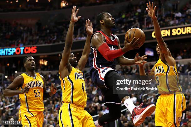 John Wall of the Washington Wizards puts up a shot between Solomon Hill and George Hill of the Indiana Pacers in the first half at Verizon Center on...