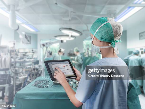 surgeon using digital tablet - chirurgenkappe stock-fotos und bilder