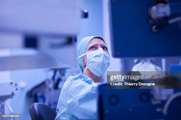 anethetist checking external bloodstream on monito - female surgeon mask - fotografias e filmes do acervo