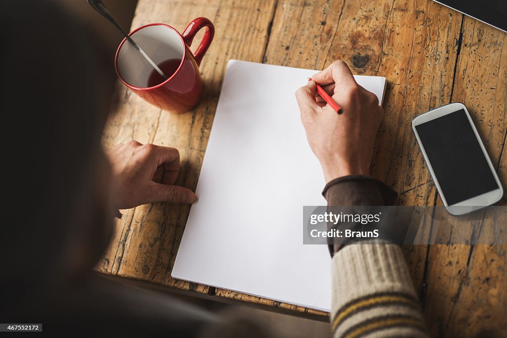 Vista de arriba de persona irreconocible escrito en papel. Espacio de copia