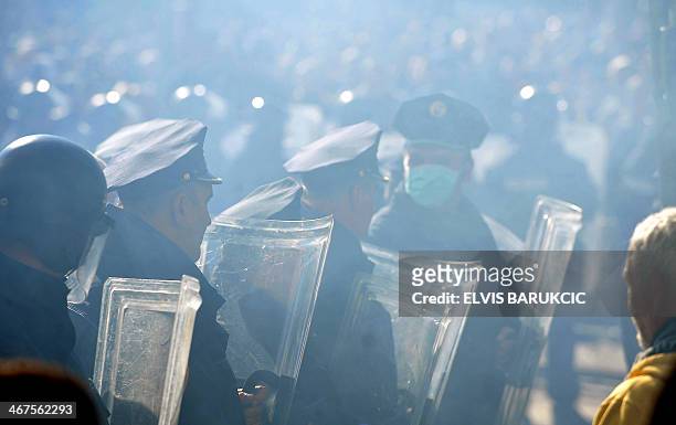 Police stand guard while protesters gather in front of a local government building in the northern Bosnian town of Tuzla, on February 7, 2014....