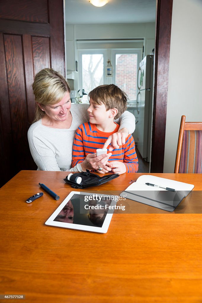 Juvenile diabetic patient testing blood sugar with his mother