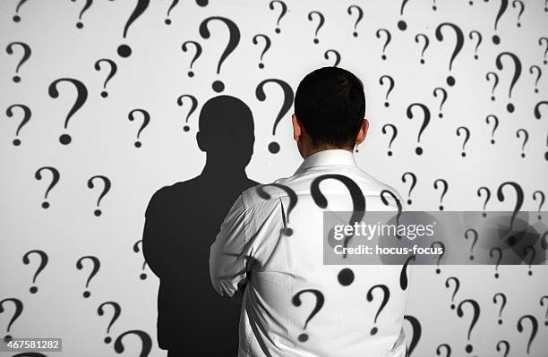 businessman standing in front of question marks - manquestionmark stock pictures, royalty-free photos & images