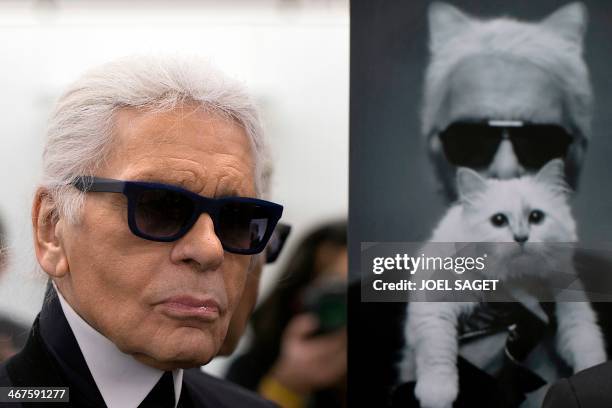 German fashion designer Karl Lagerfeld poses next to a photo of himself and his cat Choupette during a visit to the workshops that work for Chanel in...