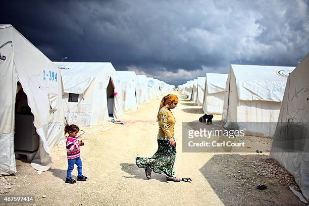 Syrian woman and child walk between tents in Suruc refugee camp on March 25, 2015 in Suruc, Turkey. The camp is the largest of its kind in Turkey...